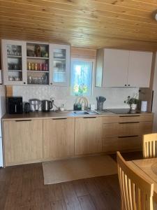 a kitchen with wooden cabinets and a sink and a table at Domek na wzgórzu in Tabaszowa