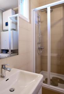 ein weißes Bad mit einer Dusche und einem Waschbecken in der Unterkunft Dalmatian Stone House in Baška Voda