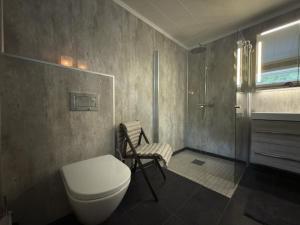 a bathroom with a toilet and a chair in it at Flakstadveien - Sentralt, midt i Lofoten in Napp