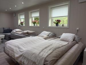a large bed in a bedroom with two windows at Flakstadveien - Sentralt, midt i Lofoten in Napp
