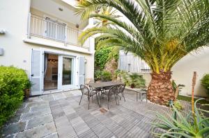 a patio with a table and chairs and a palm tree at Résidence Les Palmiers by Connexion in Cannes