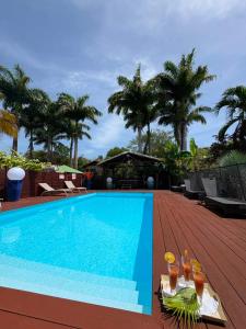 a pool with drinks on a deck with palm trees at Gite d'Arles Bungalow "Orchidée" in Le Moule