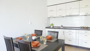 una cucina con tavolo e sedie e una cucina con armadietti bianchi di Apartament Słoneczny a Darlowko