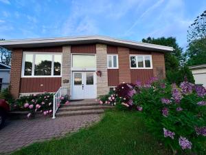 a brick house with flowers in front of it at Bright Private Room near Montreal Fast WiFi in Brossard
