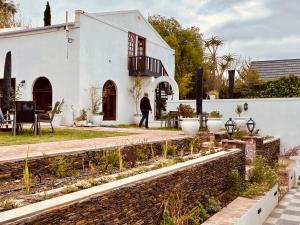 a person standing in front of a white house at KAROO ART HOTEL 4 Star in Barrydale