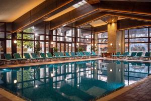 ein Schwimmbad mit Stühlen und ein Gebäude in der Unterkunft Hotel Pirin SKI & SPA in Bansko + 53 Fotos