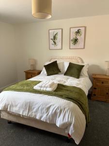 a bedroom with a large bed with white sheets and green pillows at 25 Birch House in Oswestry