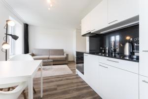 a kitchen with white cabinets and a white table at TouchBed in St. Gallen +24 photos