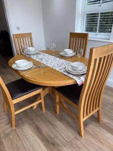 a wooden table with chairs and plates and wine glasses at 25 Birch House in Oswestry +5 photos