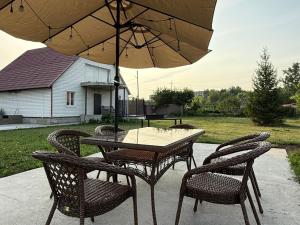 a table and chairs with an umbrella on a patio at Дом с бассейном и мангальной зоной in Ustʼ-Kamenogorsk