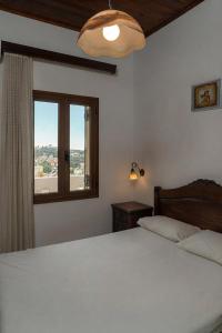 a bedroom with a white bed and a window at Thodorou Sunset Villa in Stalos