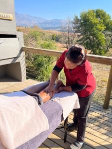 a woman is working on a table on a porch at Drakensberg Inkosana Lodge in Champagne Valley