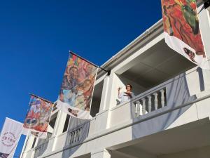 a man standing on the balcony of a building with flags at KAROO ART HOTEL 4 Star in Barrydale
