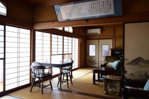 ein Zimmer mit Tisch, Stühlen und Fenstern in der Unterkunft Otowa音和 in Kijimadaira