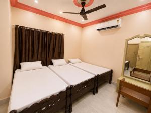 two beds in a room with a mirror and a ceiling fan at Evergreen Bungalows in Dwarka +11 photos