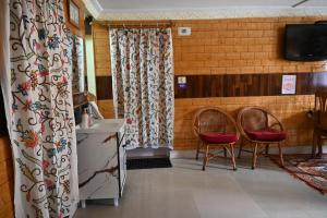 a room with two chairs and a sink and a television at Himalayan Cottages Pahalgam in Pahalgām