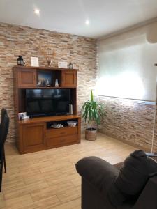 a living room with a television and a brick wall at Apartamento El Capricho in Cudillero