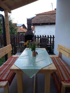 a wooden table with a vase of flowers on a patio at Smestaj kod Sneze in Dojkinci