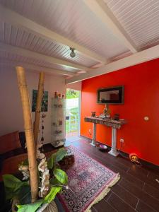 a living room with a red wall and a table at Gite d'arles Bungalow "La Rose" in Le Moule