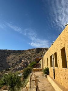 a building with a mountain in the background at Dana Village lodge and Camp-Wadi Dana Eco camp in Dana