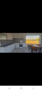 a kitchen with a table and chairs and a window at Cameră de inchiriat și Camping La Agop in Murighiol