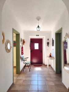 a hallway with a red door and a chair at Refúgio do Artur - Casa no Campo in São Marcos do Campo