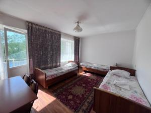 a living room with two beds and a window at Ala-Too Hotel in Naryn