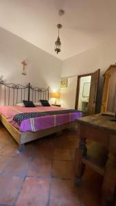 a bedroom with a bed with purple sheets and a table at Hotel Casa Santos Guanajuato in Guanajuato