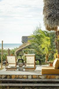 two chairs on a patio with the ocean in the background at Yvytu - Ohana Bungalow in Tatajuba