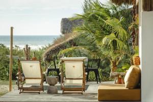 a group of chairs sitting on a porch with the beach at Yvytu - Ohana Bungalow in Tatajuba +32 photos