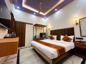 a bedroom with a large bed and a tv at Hotel CozyKey Rajpur Road in Dehradun