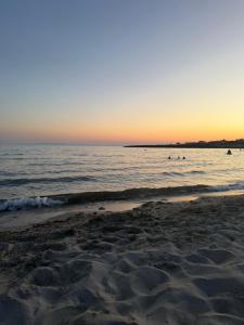 a beach at sunset with the ocean in the background at La dimora del borgo antico in Pulsano +1 photo