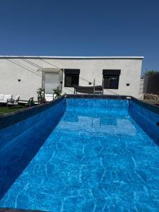 a large blue swimming pool in front of a house at אחוזת תכשיט in Sifsufa