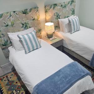 a bedroom with two beds and a lamp on a table at Aandster in Paternoster