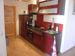 a kitchen with red cabinets and a sink at Ferienwohnung-Rurseeidyll in Simmerath