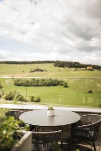 ein Tisch und Stühle auf einem Balkon mit einem Golfplatz in der Unterkunft Hotel Alpenflora in Kastelruth