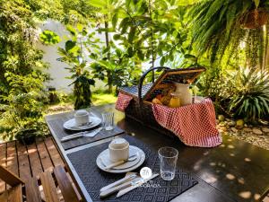 a table with plates and cups and a basket of food at Pousada Ondas da Grande - Penha/SC in Penha