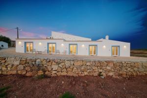 a large white house with a stone wall at Herdade do Cascalhar in Vila do Bispo
