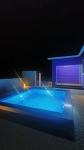 a swimming pool at night with a blue building at Vihanka villa in Tāhārpur