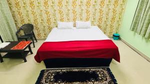a bedroom with a bed with a red blanket and a chair at New royal dormitory in Raipur