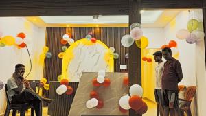 three men standing in front of a table with balloons at Hotel Janki Inn in Deoghar