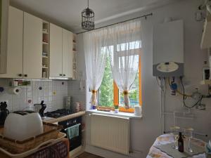 a kitchen with a sink and a window with curtains at Mery in Craiova