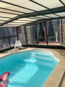 a large swimming pool with an awning and a chair at La P'tit' Fugue in La Bouexière