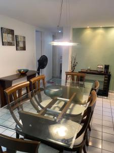 a dining room with a glass table and chairs at Apto com localização privilegiada e piscina - Charmoso e completo in Recife +15 photos