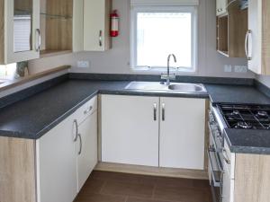 a kitchen with white cabinets and a sink and a window at Birch 2 - Ukc8215 in Pendine