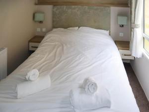 a white bed with two rolls of towels on it at Birch 2 - Ukc8215 in Pendine