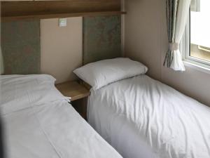 two beds in a small room with a window at Birch 2 - Ukc8215 in Pendine