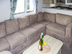 a brown couch with a bottle of wine on a table at Birch 2 - Ukc8215 in Pendine +2 photos