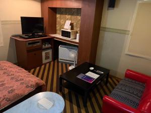 ein kleines Hotelzimmer mit einem Bett und einem Tisch in der Unterkunft ロコズリゾートハワイandオアフ in Honjo