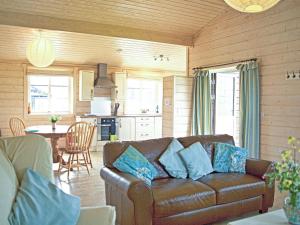 a living room with a couch and a kitchen at Lapwing Lodge - Uk51640 in Carsethorn
